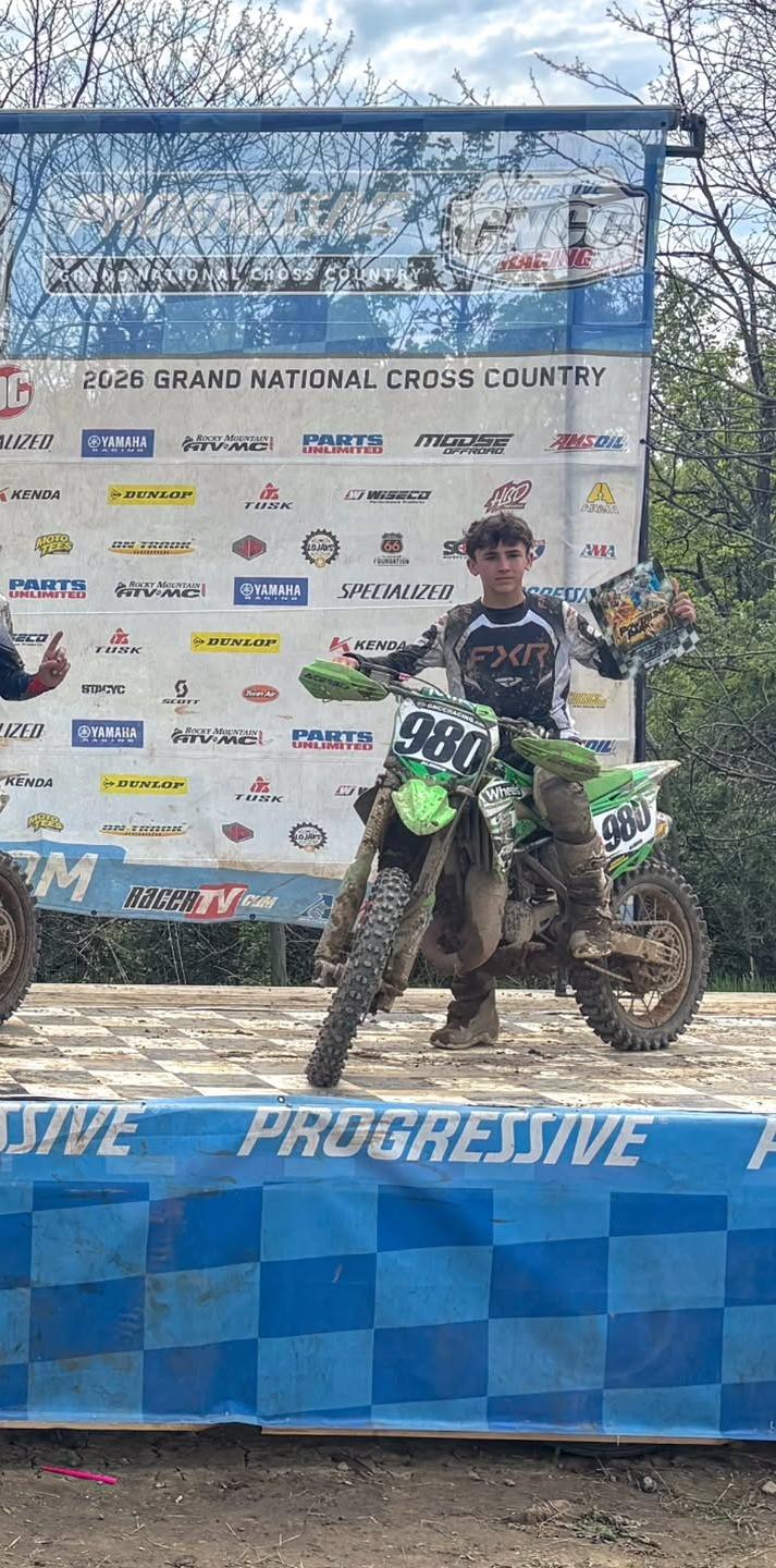 Tucker Aldrich on the #980 Kawasaki after a race, holding a podium plaque